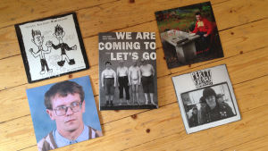 Boken och sjutumsvinyler Pertti Kurikan Nimipäivät boken We are coming to let´s go samt fyra vinylsinglar av bandet på ett trägolv