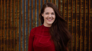 Kaarina Kolle på WWF Europa tycker att branscher med höga utsläpp inte borde finnas med i ESG-placeringar överhuvudtaget, när utsläppen borde minska mycket snabbt. Bild: Aki-Pekka Sinikoski / WWF En leende ung kvinna med långt brunt hår och vinröd tröja.