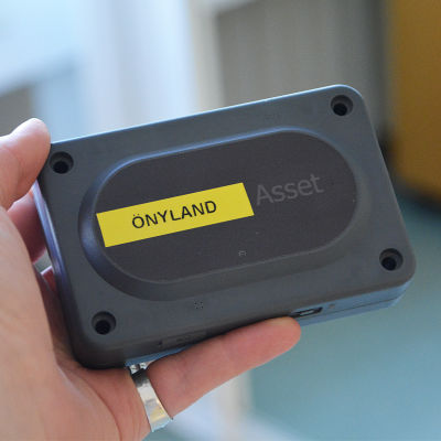 En hand håller i en fyrkantig svart plastdosa. På dosan står det önyland.