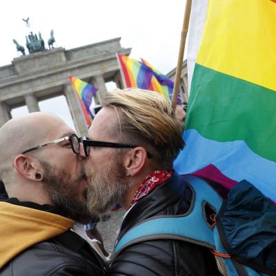 miehet suutelevat, taustalla Brandenburgin portti ja sateenkaarilippuja.