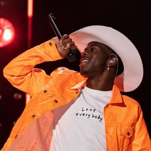 Lil Nas X bär cowboyhatt och sjunger i en mikrofon som han håller i handen.