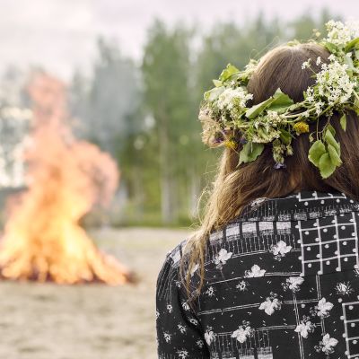 Nuori nainen katsoo juhannuskokkoa.