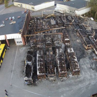 Ilmakuva, jossa palaneita linja-autoja tuhopolton jäljiltä.
