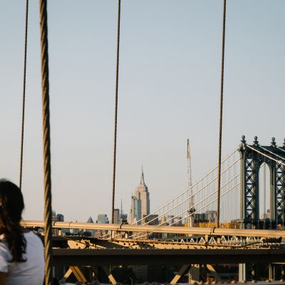 Nainen katsoo New Yorkin Brooklyn Bridgelle Brooklynissa. Takana siintää kaupungin pilvenpiirtäjä, joukossaan Empire State Building.