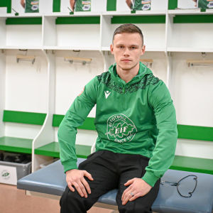 En man sitter på en bänk klädd i fotbollslaget EIF:s gröna tröja. Han heter Tobias Fagerström.