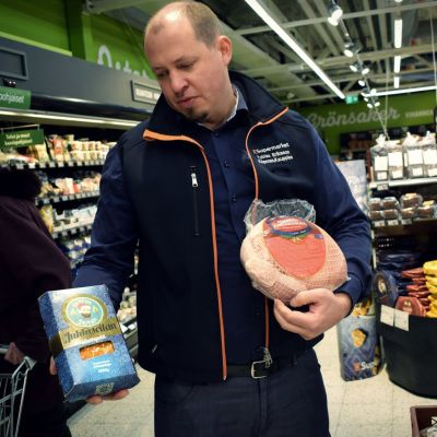 Köpman Tobias Eriksson håller en mindre skinka och en vegansk julskinka i händerna i sin matbutik.