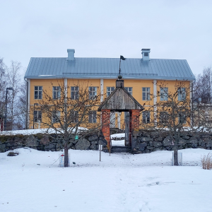 En gul gammal prästgård i vinterlandskap. 