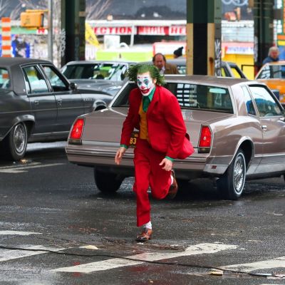 Jokeriksi maskeerattu Joaquin Phoenix juoksee kadulla.