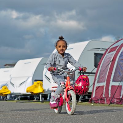 5-vuotias eritrealainen Divora polkee pyörällään matkailuautorivistön ohi. Saksan Frankfurtissa sijaitsevaan Rebstockin puistoon oli sijoitettu hieman yli sata rekisteröityä pakolaista helmikuussa 2016.