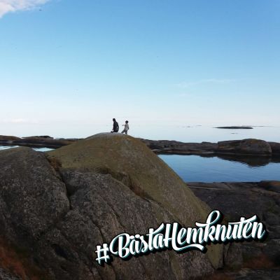 Två personer på avstånd på en klipphäll vid havet