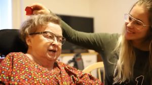 Arkivbild. Pirkko Martikainen i blommig klänning tillsammans med sin personliga assistent.