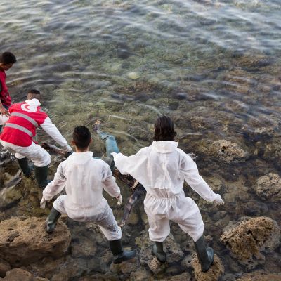 Libyan Punaisen Ristin edustajat poistavat vedestä Välimereen hukkuneen siirtolaisen ruumiin Libyan rannikolla.