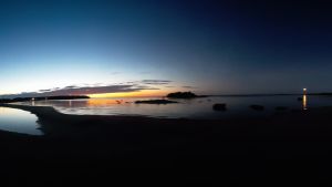 Solnedgång och nästan fullmåne samtidigt på en av parets resor. Solnedgång och måne ovanför mörkt vatten.