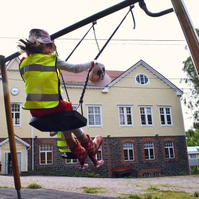 Ett förskolebarn gungar i hård fart på gården till Dalsbruk skola.
