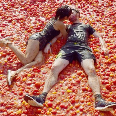 Pariskunta suutelee tomaattien päällä tomaattisota-festivaalilla Venäjällä.