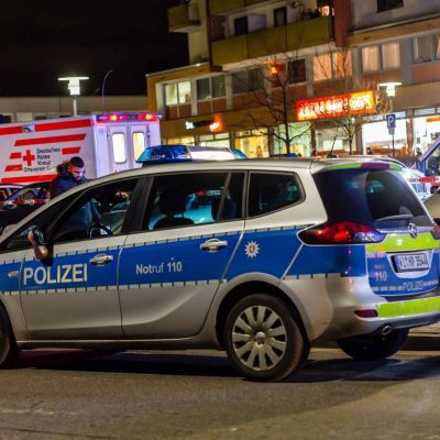 Poliisiauto edustalla. Taustalla ambulanssi ja taloja.