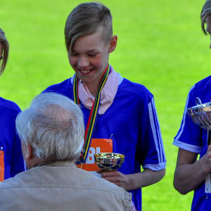 En välförtjänt vinst. adam på guldpodiet med en pokal i handen och en medalj runt halsen