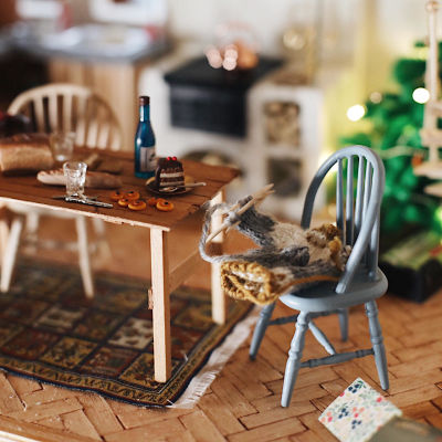Ett dockhuskök med lussebullar på bordet och en julgran.