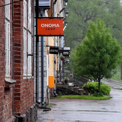 butiksskylt på vägg och gröna träd i bakgrunden