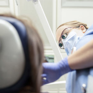 Hammaslääkäri tutkii potilaan suuta hoitopöydällä.