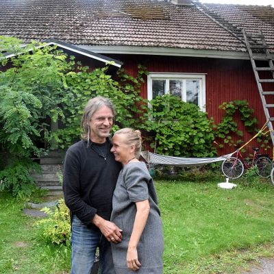 man och kvinna på gårdsplan till rött trähus