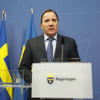 Stefvan Löfven, taustalla kaksi Ruotsin lippua.