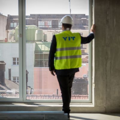 Mies katselee ikkunasta ulos maisemaa.