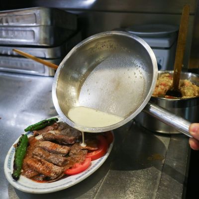 Iskender-kebab viimeistellään kaatamalla annoksen päälle rasvaa.
