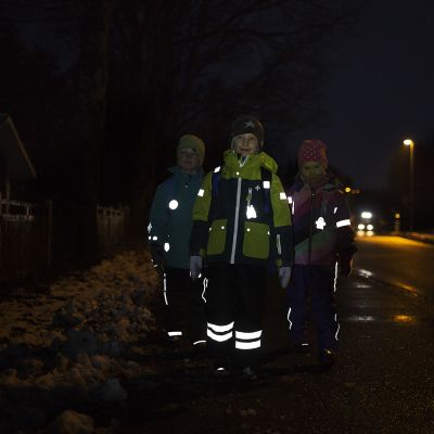 Heijastinta käyttäviä lapsia pimeällä kadulla.