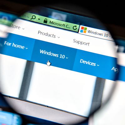Suurennuslasin läpi näkyy tietokoneen näytöllä Windows 10:n alavalikko ja käsi-ikoni.