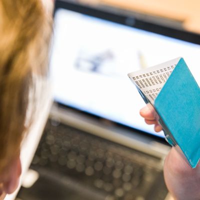 Mies selaa verkkopankkia avainlukulista kädessään.