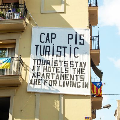 Talon seinään ripustettu lakana kehottaa turisteja yöpymään hotelleissa.