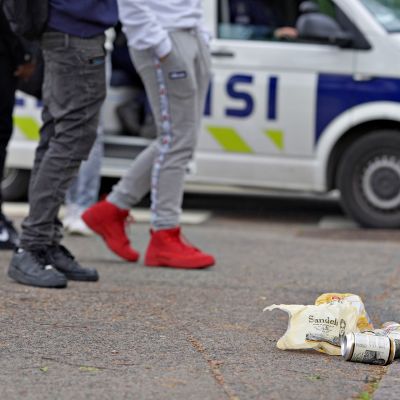 Oluttölkkejä Esplanadin puistossa Helsingissä lauantai-iltana ensimmäinen kesäkuuta 2019. Poliisiauto taustalla.