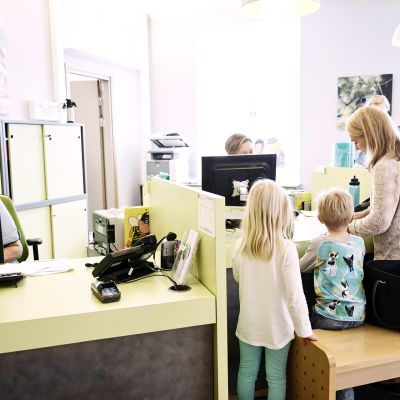 Äiti lapsineen lääkäriaseman vastaanottotiskillä Helsingissä