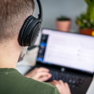Mies työskentelee etänä kannettavalla tietokoneella.