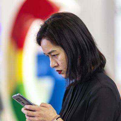 Nainen selaa puhelinta Googlen logon edustalla messuilla Guiyangissa Kiinassa