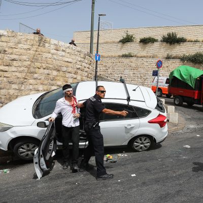 Israelilaine npoliisi osoittaa aseella palestiinalaismiestä.