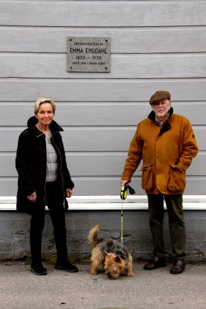 Satu Torstila, Bo Wessman och hunden Lufsi framför huset på Östra strandgatan som sångerskan Emma Engdahl bodde i. kvinna och man invid husvägg