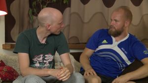 kaksi miestä keskustelevat kärkkäästi sohvalla