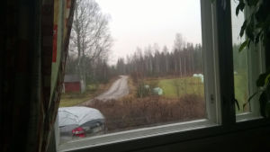 Kuva ikkunasta ulos pihatielle, jossa maalaismaisemaa.