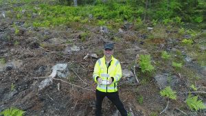 Romi Rancken granskar en avverkning med en drönare i en skog i Raseborg Romi Rancken är drönarpilot och forstmästare.