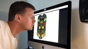 Kustrock:s programledare Joakim Rundt synar bistert Sammals logo i detalj. En man sitter vid en dator.