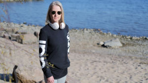 - Det var inte många som trodde på mig men nu kan jag tala och skriva, inte som förut men långt mera än de trodde. Jag går långsamt men utan käpp, säger Christa Mickelsson. Kvinna med blong page och svarta solglasögon står vid en strand en solig vår dag.