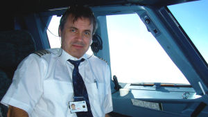 Stefan Vikström är trebarnsfar och pilot En medelålders manlig flygpilot sitter i ett flygplan och tittar mot kameran