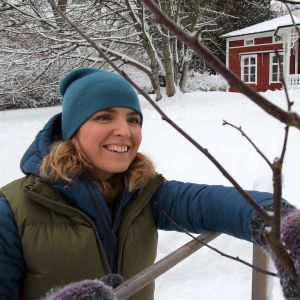 Lena Gillberg invid ungt äppelträd framför Strömsövillan