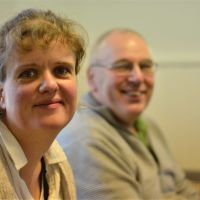 Kvinna med lockigt hår ser rakt in i kameran och småler.