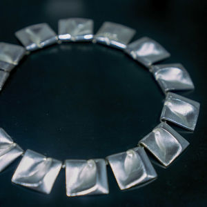 Ett stort halsband i silver med svart bakgrund.