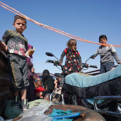 Lapset seisovat avolava-auton lavalla Syyriassa. Auto on matkalla pois taisteluiden alta.