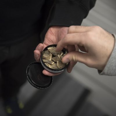 Mies ottaa toisen miehen tarjoamasta nuuskarasiasta nuuskapussia.