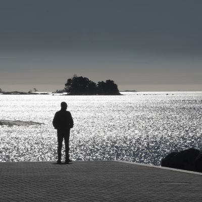 Mies seisoo laiturilla ja katsoo merelle